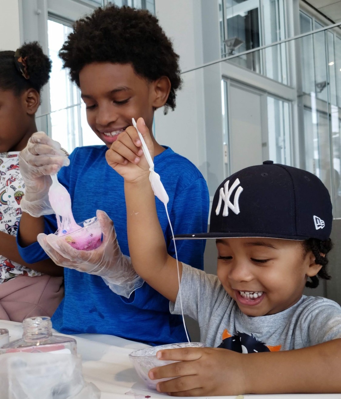 Two children stand alongside each other as they make slime solutions together during the Wellness Center's 'Slime Time' event for Manhattanville's Community Day in April 2019.
