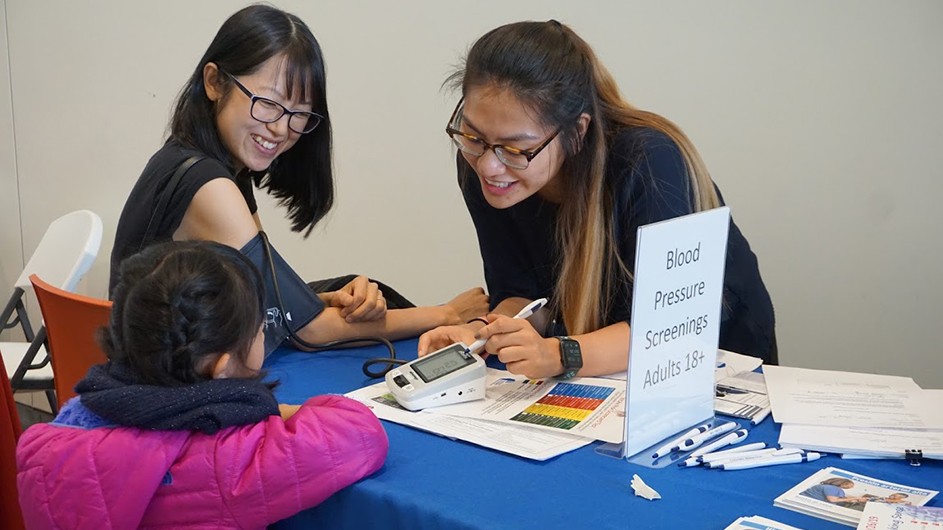Mother at Saturday Science event has her blood pressure screening done while her daughter watches. (Credit: Paula Croxson/Zuckerman Institute)